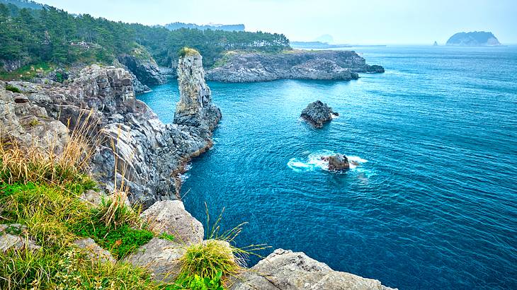 Rocky cliffs surrounded by blue water and green hills