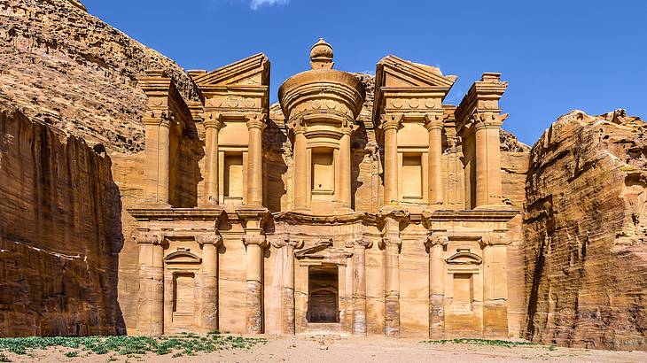 A rock-cut building carved out of a sandstone cliff on a sunny day