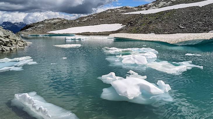 Floating icebergs on a glacial lake surrounded by small snow-covered mountains