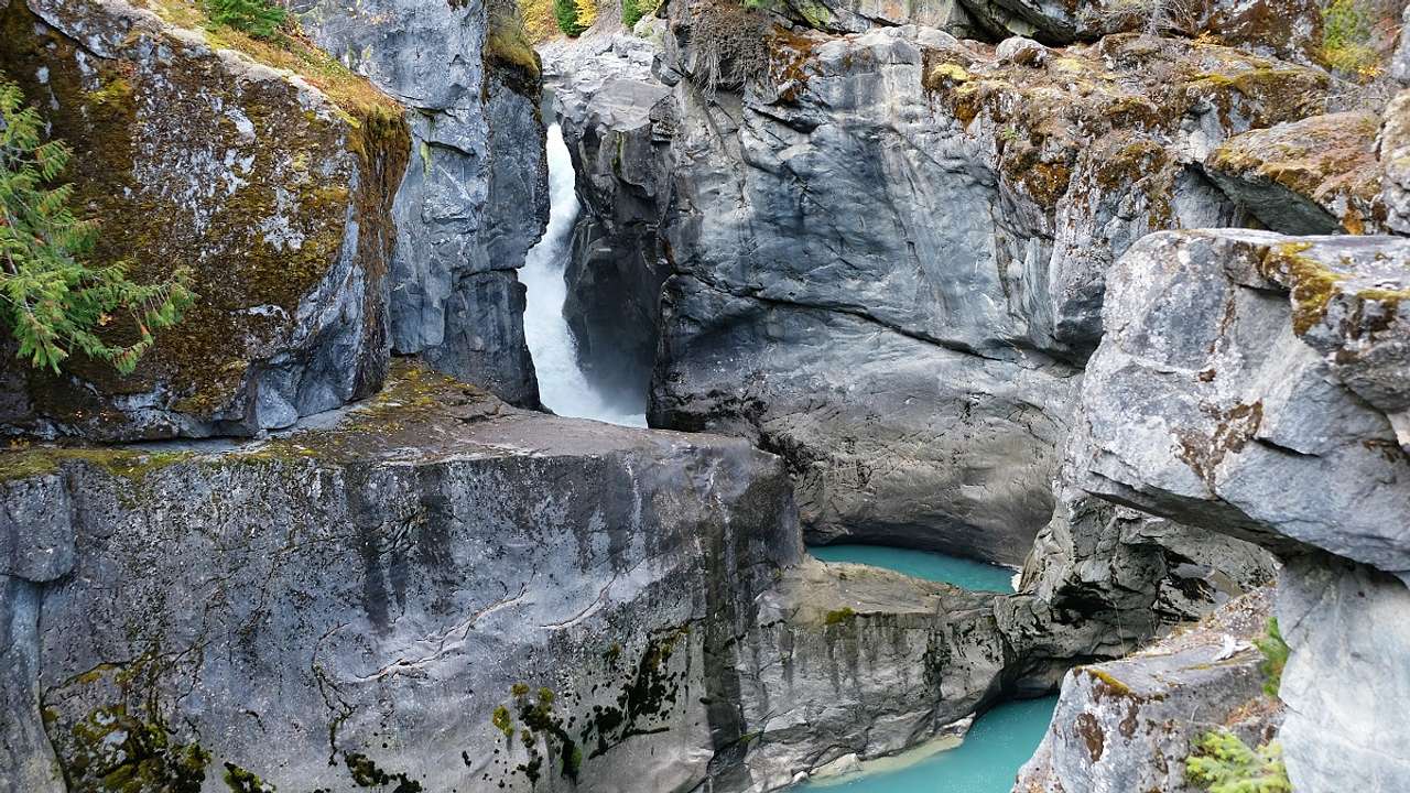 A small waterfall flowing over a rock cliff face into a turquoise pool