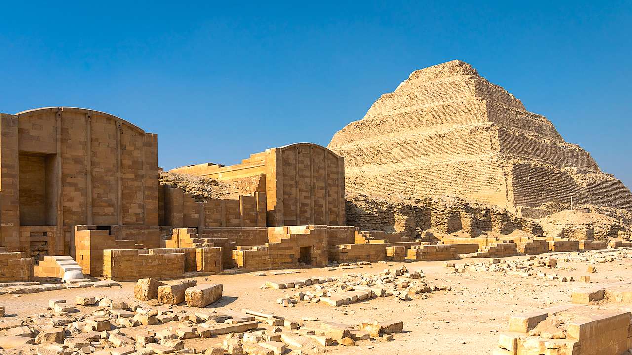 View of a pyramid and ruins against a blue sky
