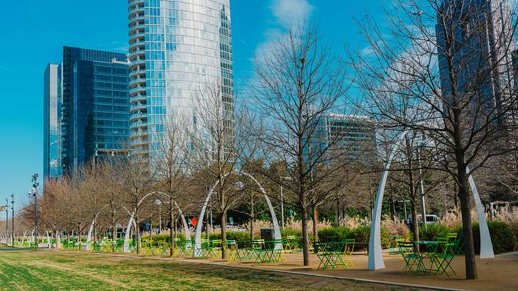 A series of archways on a walkway in a park near skyscrapers