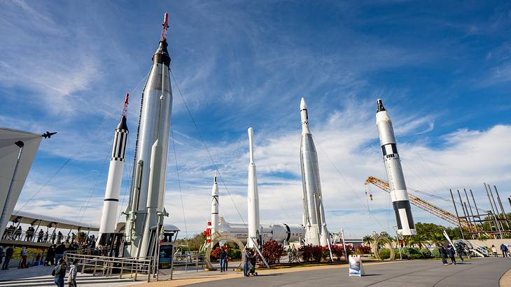 People wandering around a site with six space shuttles on a sunny day