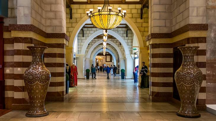 A grand entryway with large vases, a chandelier, and tiled walls