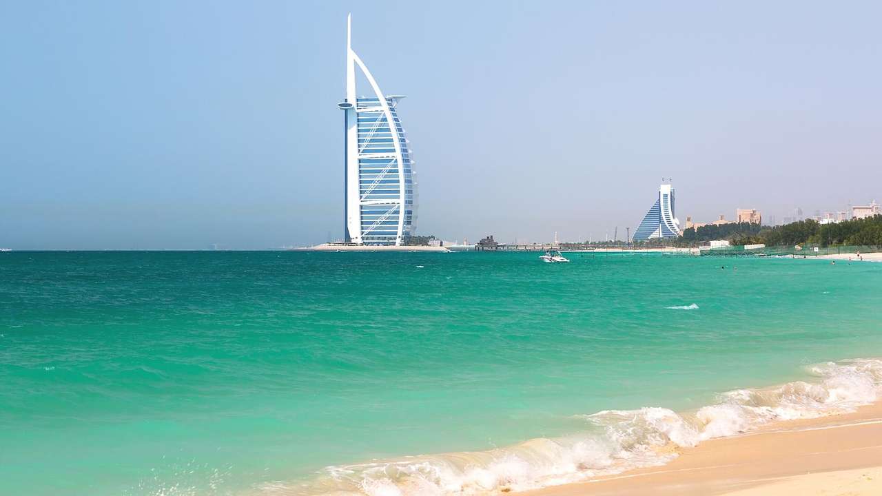 Sand and the turquoise ocean with the modern Burj Al Arab structure on the horizon