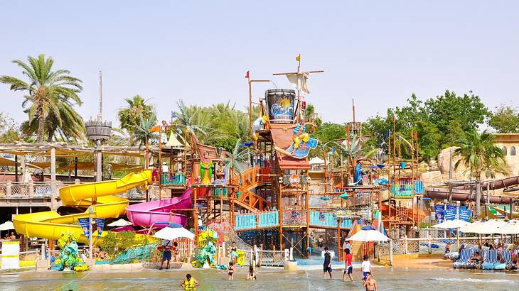 A water park with people in a pool next to colorful water slides and a pirate ship