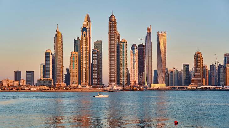 A modern city skyline next to a marina at sunset