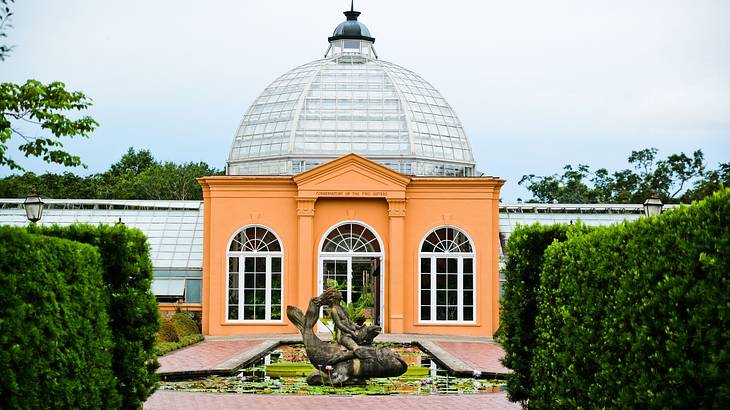 A house with a dome on top and fountain in front, surrounded by greenery