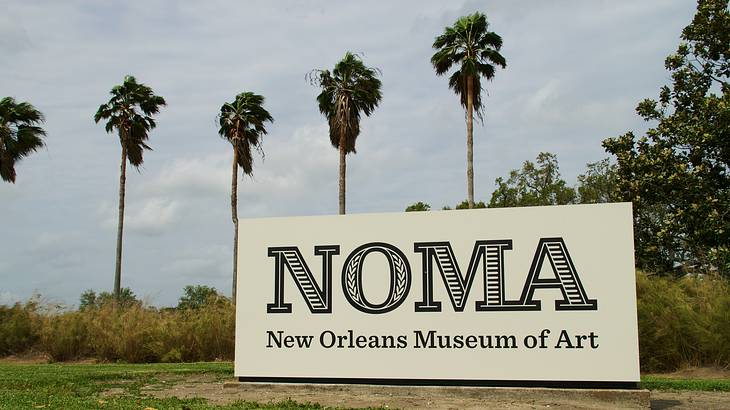 Palm trees and a big signboard on grass that reads "NOMA New Orleans Museum of Art"