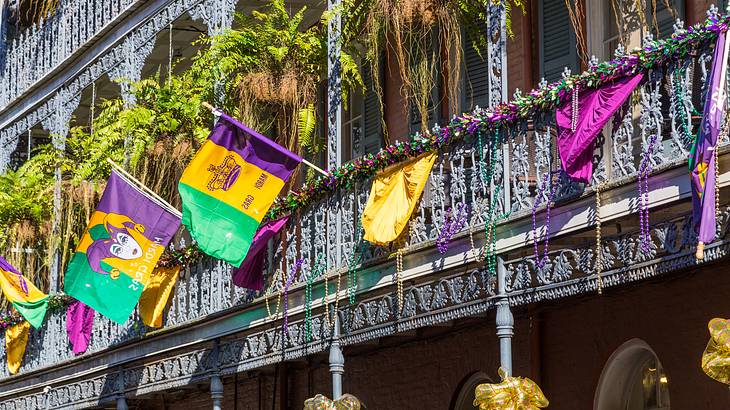 A building with ironwork galleries decorated with colourful flags and hanging plants