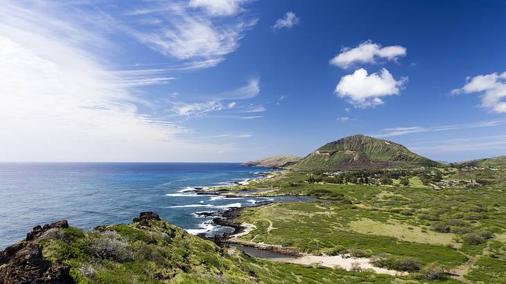 Greenery-covered cliffs with the ocean to the side under blue sky