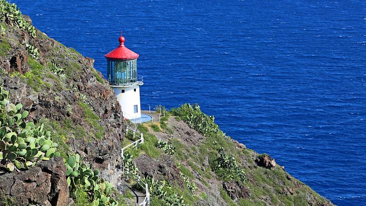 A steep trail running along the side of a mountain with a lighthouse at the end