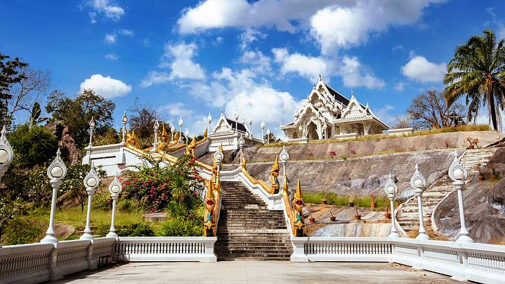 White stairs leading to a temple surrounded by plants on a cloudy day