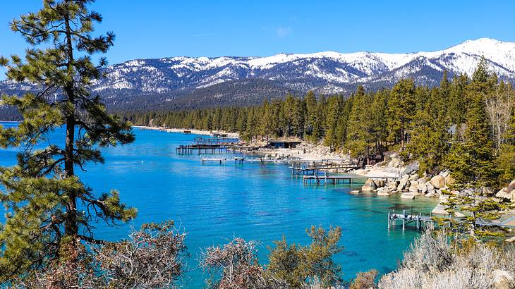 A view of a lakeside with wooden docks near trees and mountains