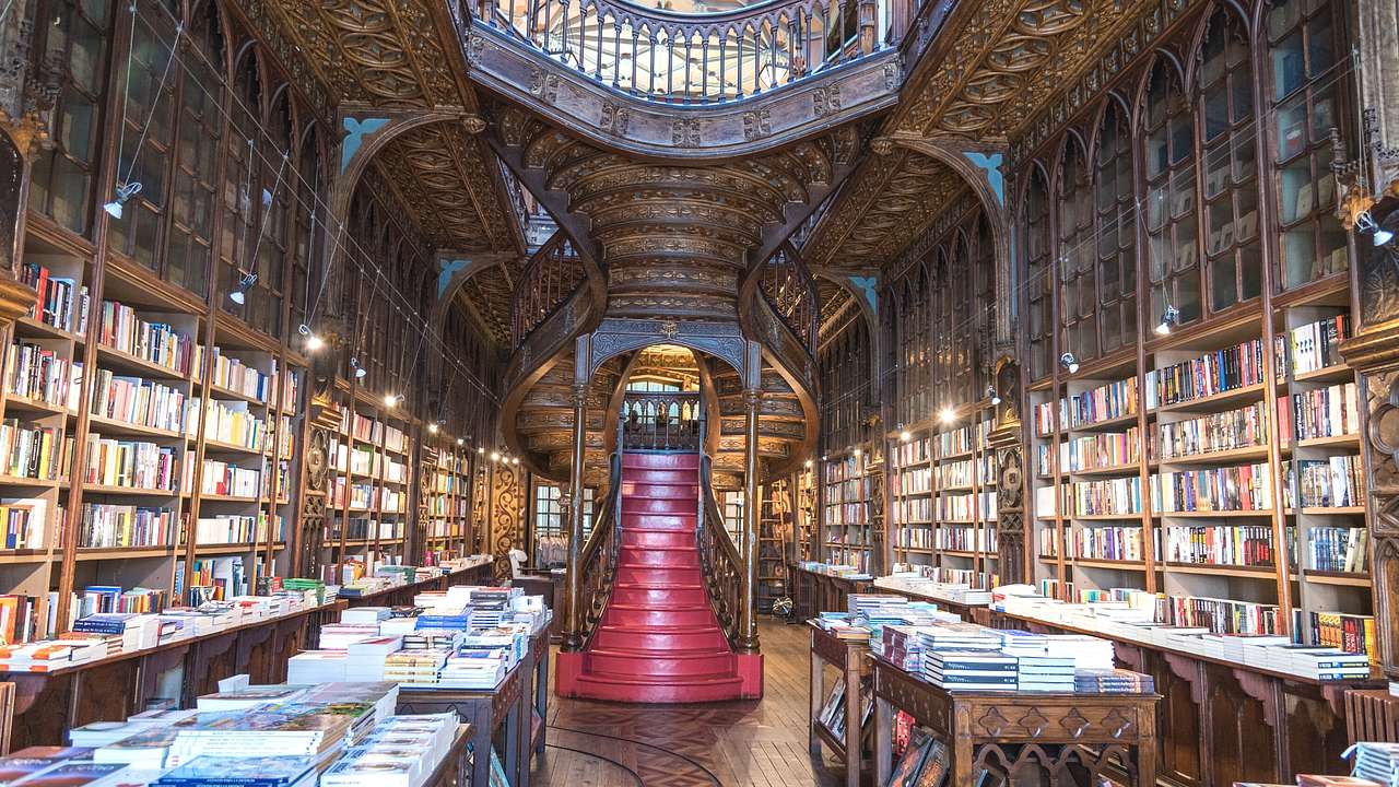 The interior of an old bookstore with a wooden staircase and bookshelves with books