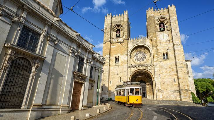 A stone cathedral with two towers next to a yellow street car on a track