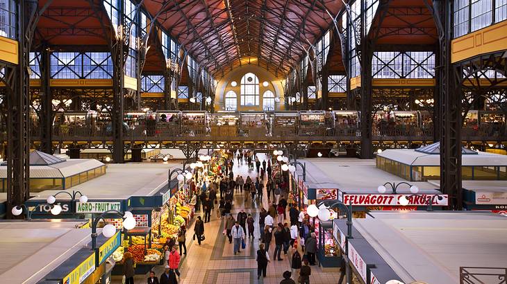 A big warehouse with many stalls selling food and people walking in between