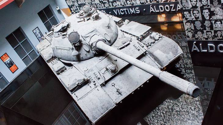 A grey army tank and a wall of photos of victims of military regimes