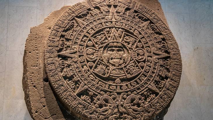 A round basalt disk with a face-like shape in the middle and a sun-designed border A round basalt disk with a face-like shape in the middle and a sun-designed border