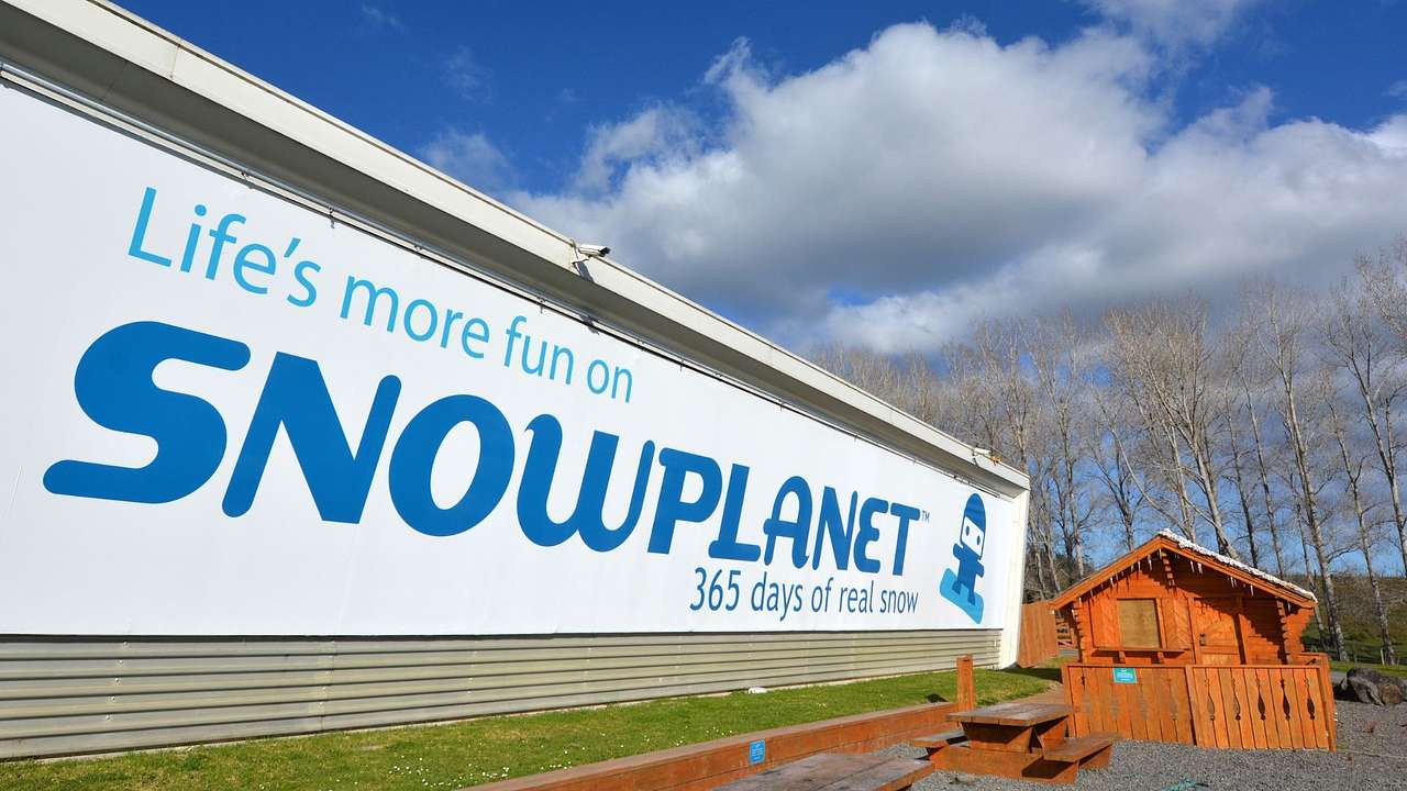 A building that says "Snowplanet" next to grass and a small wooden cabin