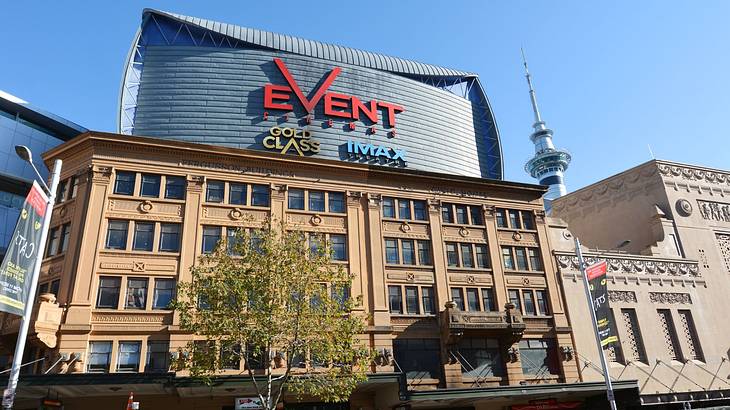 A brown building with large glass panels and a large sign under a clear blue sky