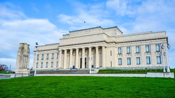 A large building with columns and a tower-like structure next to a green lawn