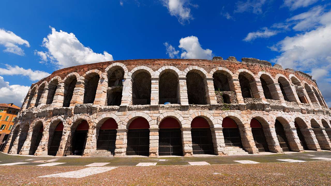 The outside architecture of a Roman amphitheater against a sunny blue sky