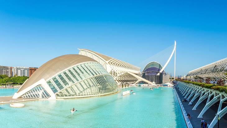 A modern dome-shaped building made of glass with water around it