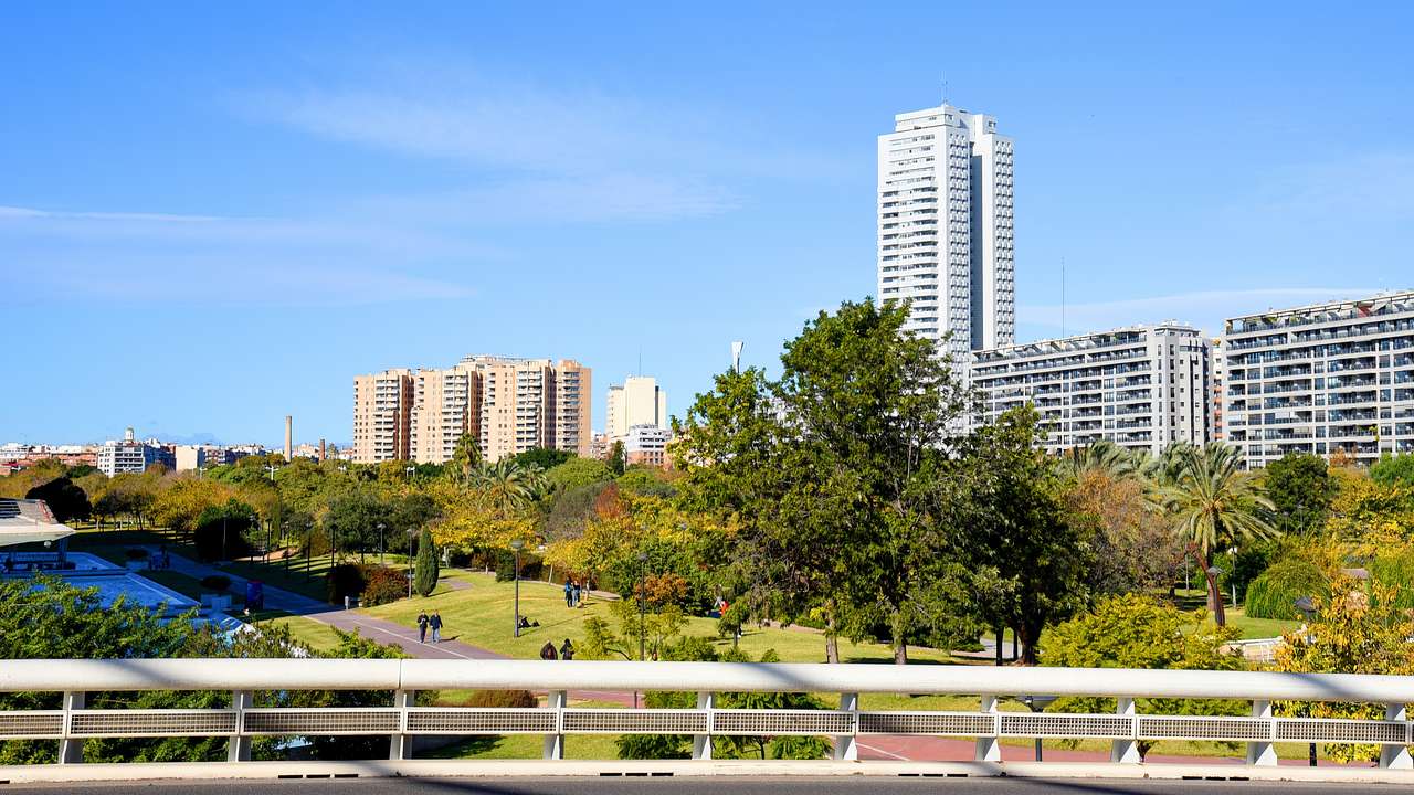 A bridge with a view of a landscaped park near skyscrapers