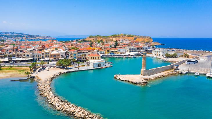 An aerial shot of a coastal village near a lighthouse and turquoise water