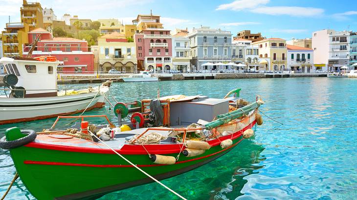 A green boat in clear water near colorful buildings