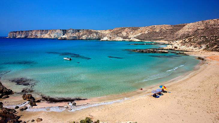 An aerial shot of a beach with umbrellas near mountains