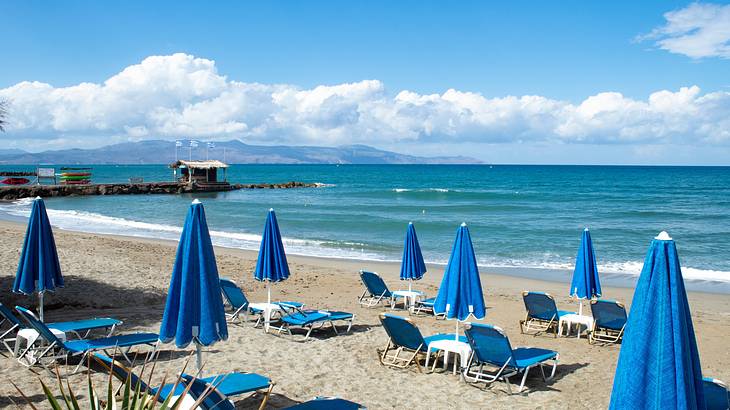 Blue umbrellas and lounge chairs by the beach