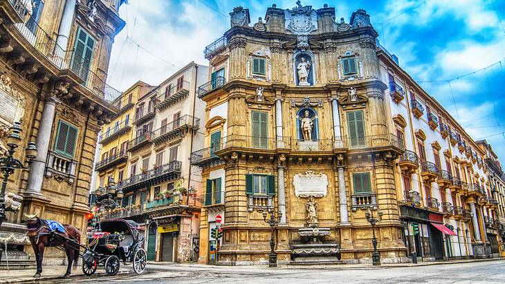 A horse carriage on a street near an intricately-designed corner building