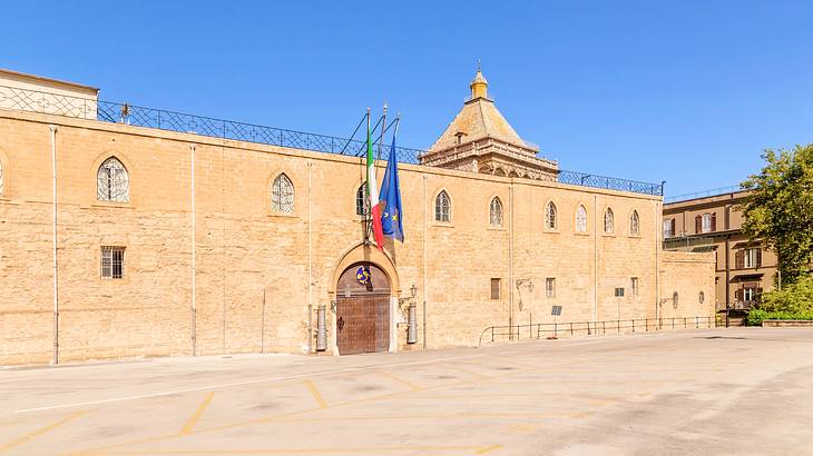 A facade of a building with hanging flags and a small tower