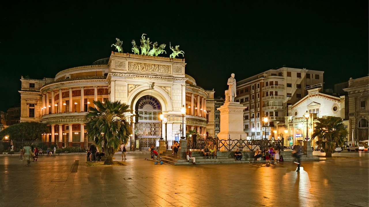 A stone arch in a square illuminated at night