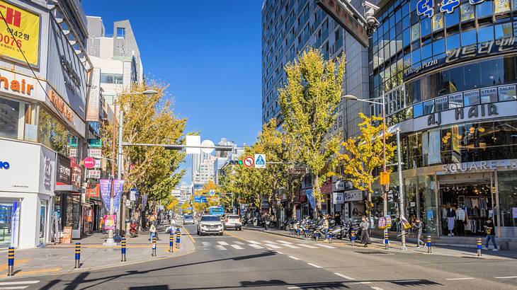 People walking the streets surrounded by cars and commercial establishments