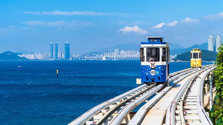 Small train capsules on a railway by the edge of the mountain near the ocean