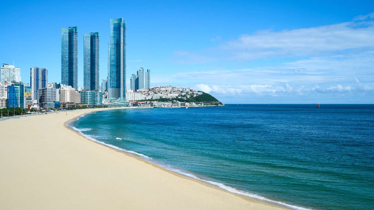 A white sand beach with skyscrapers in the horizon