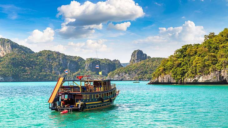 A boat on turquoise water surrounded by greenery-covered hills