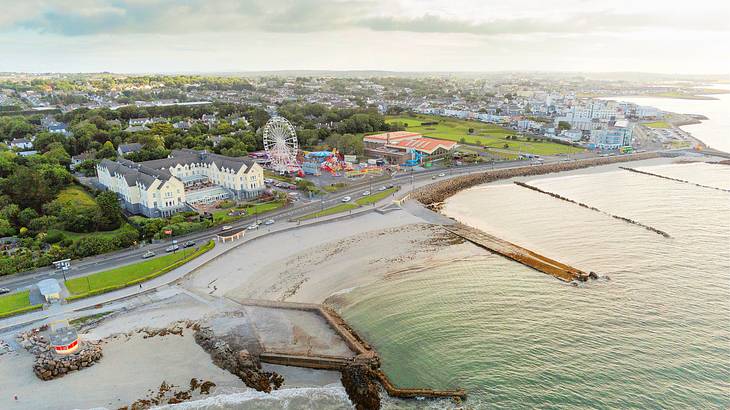 An aerial shot of a coastal town with a Ferris Wheel, roads, and a small port