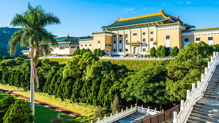 Outside of the National Palace Museum in Taipei facing a green lawn and palm trees