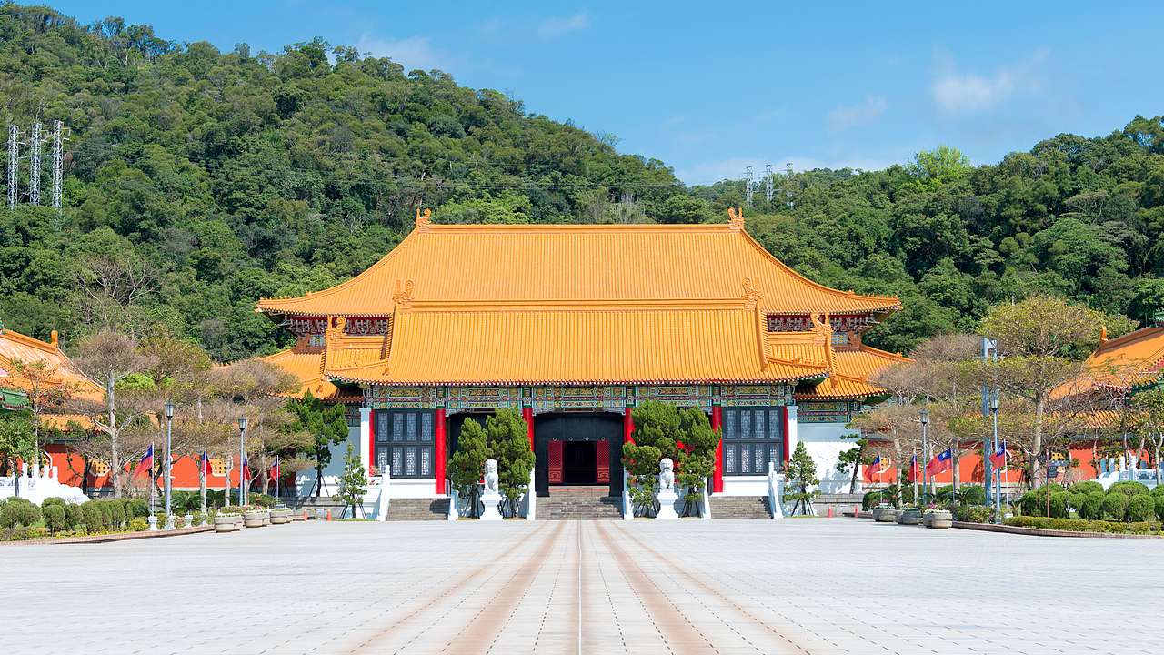 The outside of a shrine facing a courtyard, with tree-covered mountains at the back