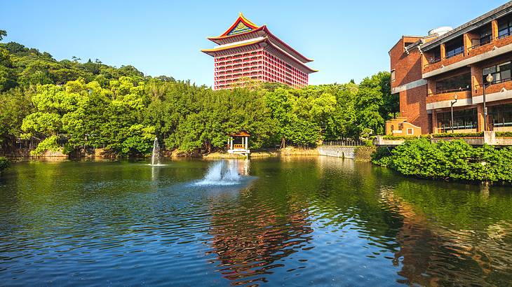 The Grand Hotel in Taipei behind water and green trees