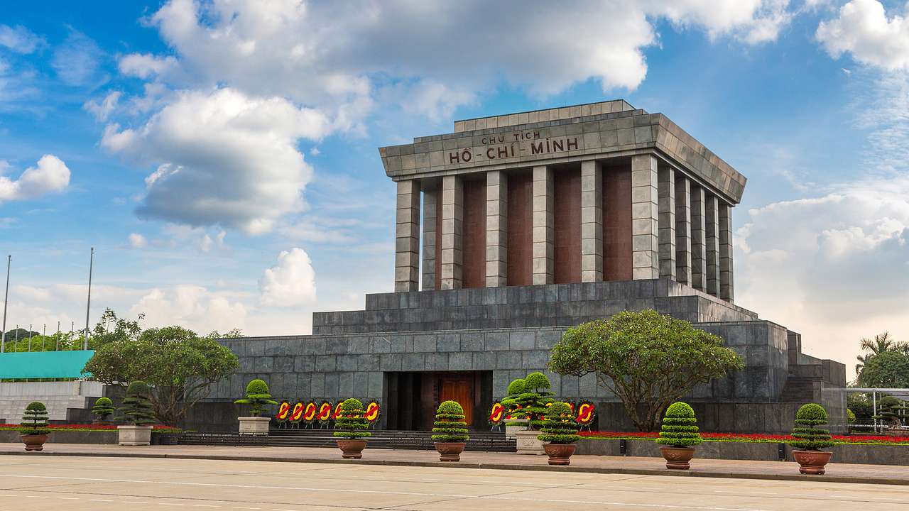 A stone building with columns and a "Ho Chi Minh" sign atop a stone foundation