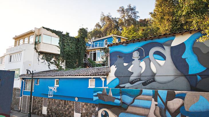 Buildings with murals on the walls in blue and gray surrounded by trees