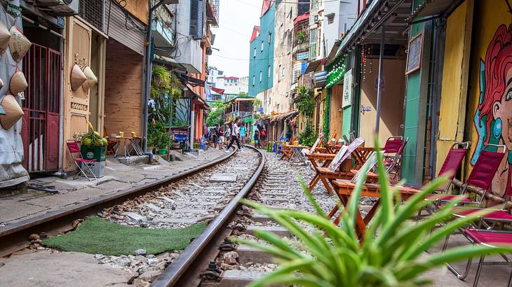 A railway track in between houses with chairs lined up outside