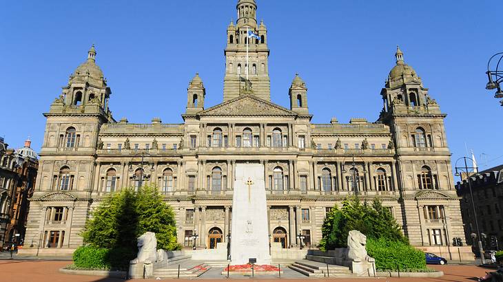 A white monument in front of an old building with a tall spire in the middle