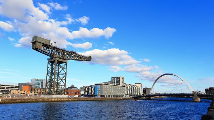 An old crane near buildings and a bridge over a river