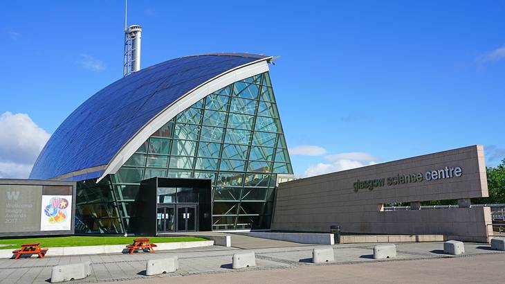 A modern glass-paneled building with a sign saying "Glasgow Science Centre"